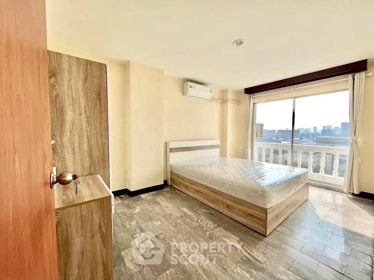 Spacious bedroom with city view and modern furnishings in high-rise apartment