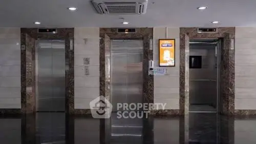 Modern building lobby with three sleek elevators and polished floors.