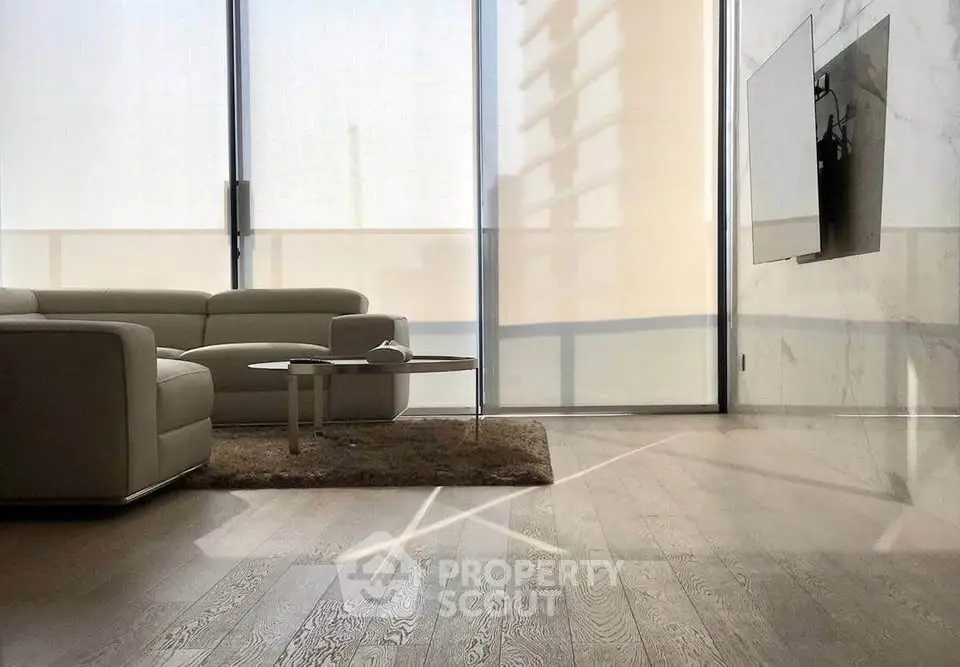 Modern living room with sleek furniture and large windows offering natural light.