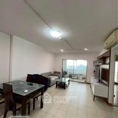 Spacious living room with modern furniture and city view balcony in high-rise apartment.