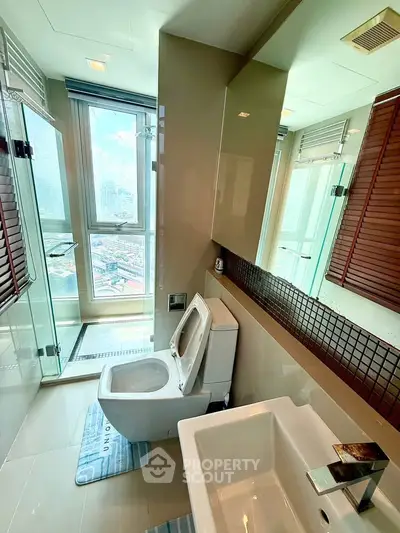Modern bathroom with city view, featuring glass shower and sleek fixtures.