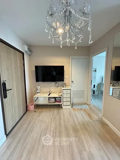 Modern living room with elegant chandelier and wall-mounted TV in stylish apartment.