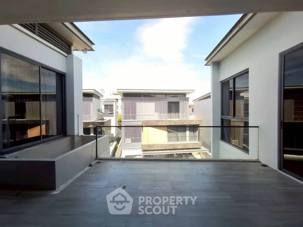 Spacious balcony with modern design overlooking contemporary buildings.