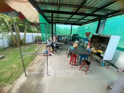 Spacious outdoor kitchen with covered roof and garden view, ideal for entertaining.