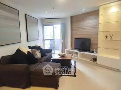 Modern living room with cozy sofa and TV, featuring stylish decor and natural light from balcony.