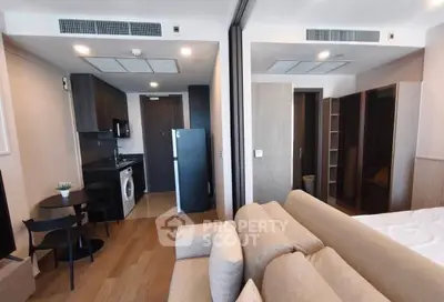 Modern studio apartment with open layout, featuring a cozy living area, compact kitchen, and washing machine.