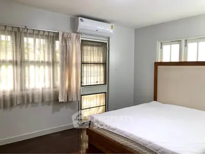 Spacious bedroom with natural light and modern air conditioning unit.