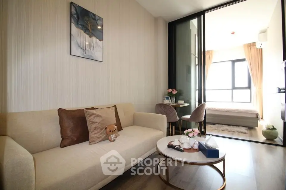 Modern living room with cozy beige sofa and stylish decor leading to a bright bedroom.