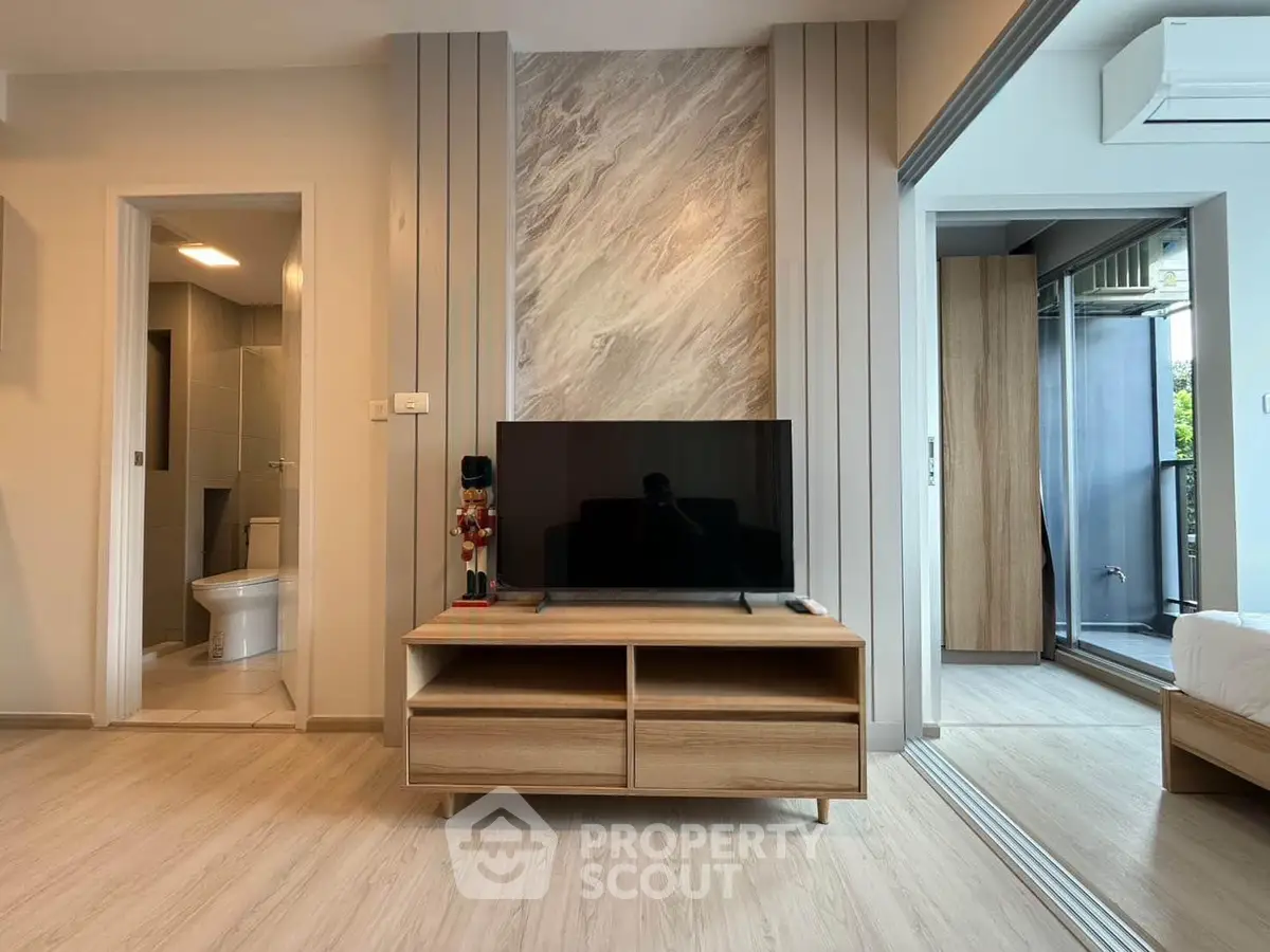 Modern living room with sleek TV stand and stylish decor, adjacent to a bathroom and bedroom.