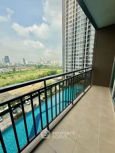 Spacious balcony with stunning city and pool view in modern high-rise apartment.