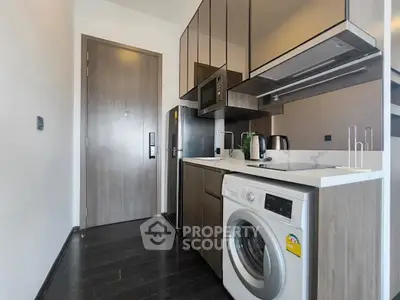 Modern kitchen with sleek cabinetry, washing machine, and stainless steel appliances in compact layout.