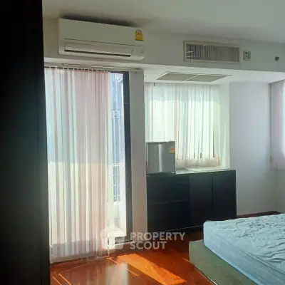 Bright bedroom with air conditioning and balcony access, featuring wooden flooring and modern decor.