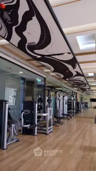 Modern gym with state-of-the-art equipment and stylish ceiling design in luxury building.