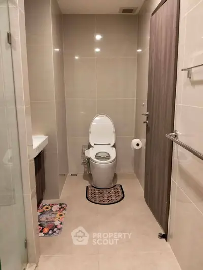 Modern bathroom with sleek design and neutral tones, featuring a toilet and stylish fixtures.