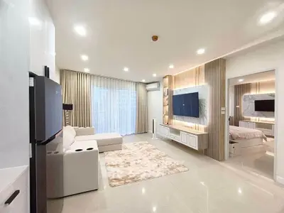 Modern living room with sleek design and large TV, adjacent to stylish bedroom.