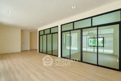 Spacious modern living room with glass partitions and wooden flooring