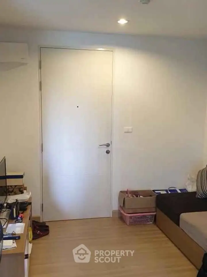 Cozy living room with modern decor and wooden flooring, featuring a sleek entrance door.