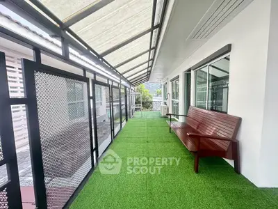 Spacious balcony with artificial grass and seating, offering a serene outdoor retreat.