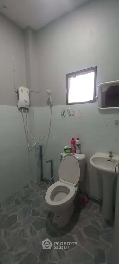 Compact bathroom with shower, toilet, and sink in a minimalist design.