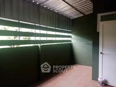 Spacious covered balcony with green walls and tiled floor, perfect for relaxation.