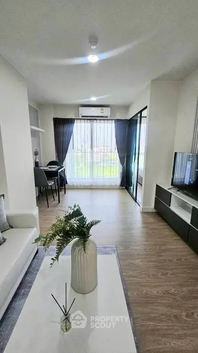 Modern living room with stylish decor and large window offering natural light.