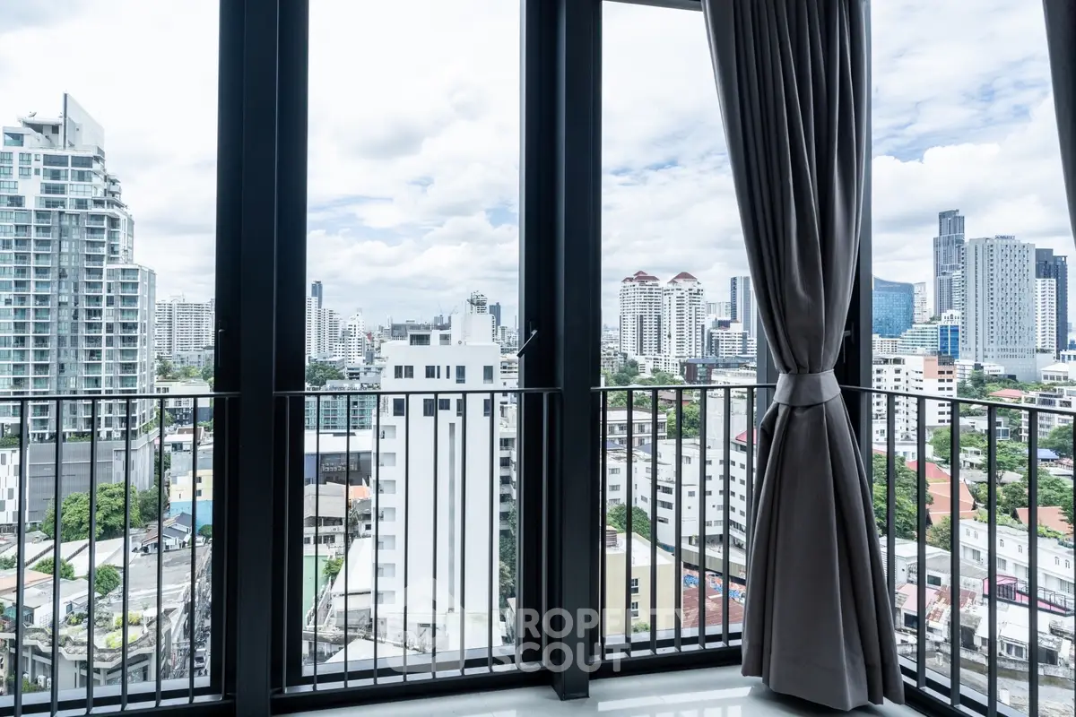 Stunning cityscape view from a modern apartment balcony with floor-to-ceiling windows.