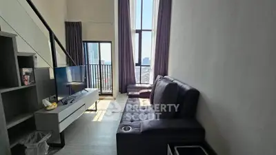 Modern living room with high ceilings and large windows offering city views.