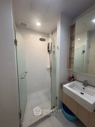 Modern bathroom with glass shower enclosure and sleek vanity in a contemporary apartment.