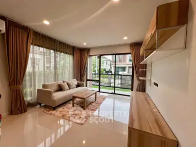 Spacious living room with modern decor and large windows offering garden view.