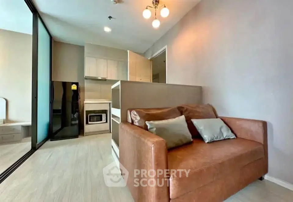 Modern living room with cozy leather sofa and sleek kitchen area in open layout apartment.