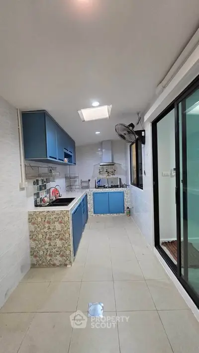 Modern kitchen with blue cabinets and open layout, featuring sleek design and ample natural light.