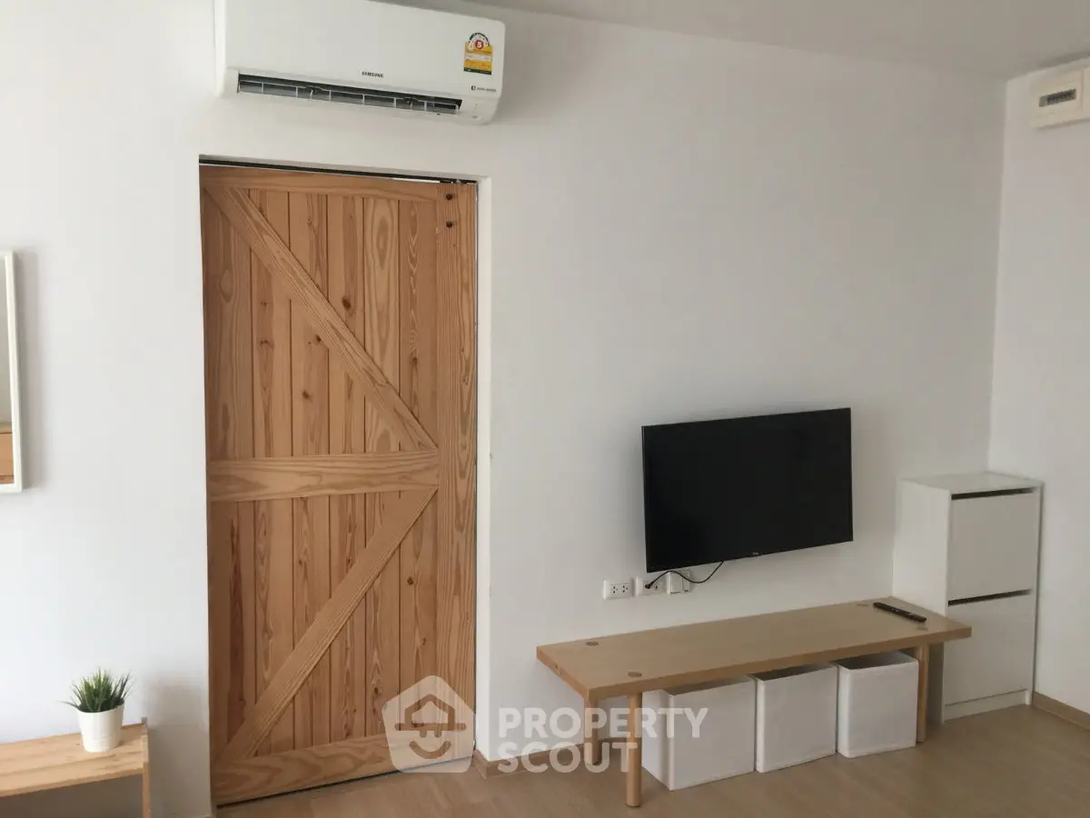 Modern living room with wooden sliding door, wall-mounted TV, and minimalist decor.