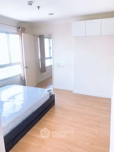 Bright bedroom with large windows and wooden flooring, featuring a comfortable bed and modern design.