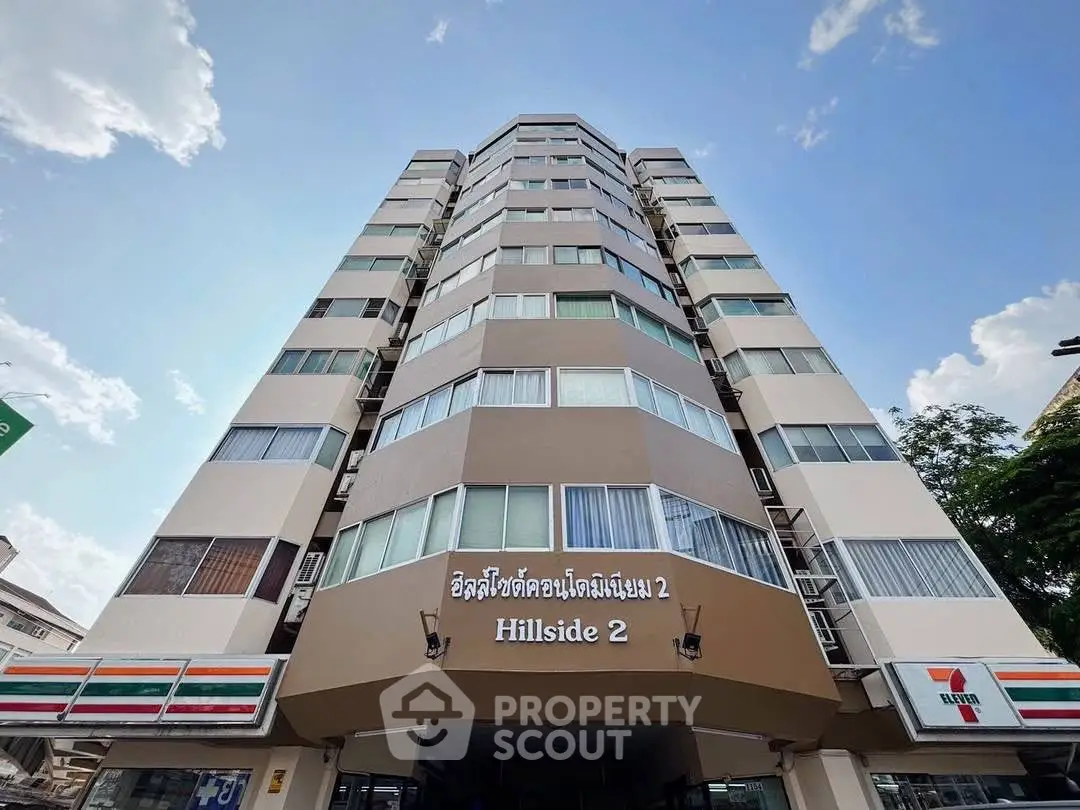 Modern high-rise building exterior with clear blue sky, showcasing urban living at Hillside 2.