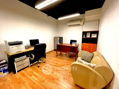 Modern home office with wooden flooring, desk, chair, and air conditioning.