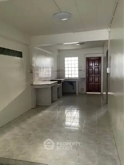 Spacious kitchen with closed layout and ample natural light, featuring tiled flooring and modern fixtures.