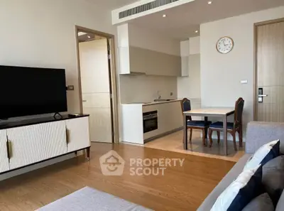 Modern living room with open kitchen and elegant dining area, featuring stylish furniture and wooden flooring.