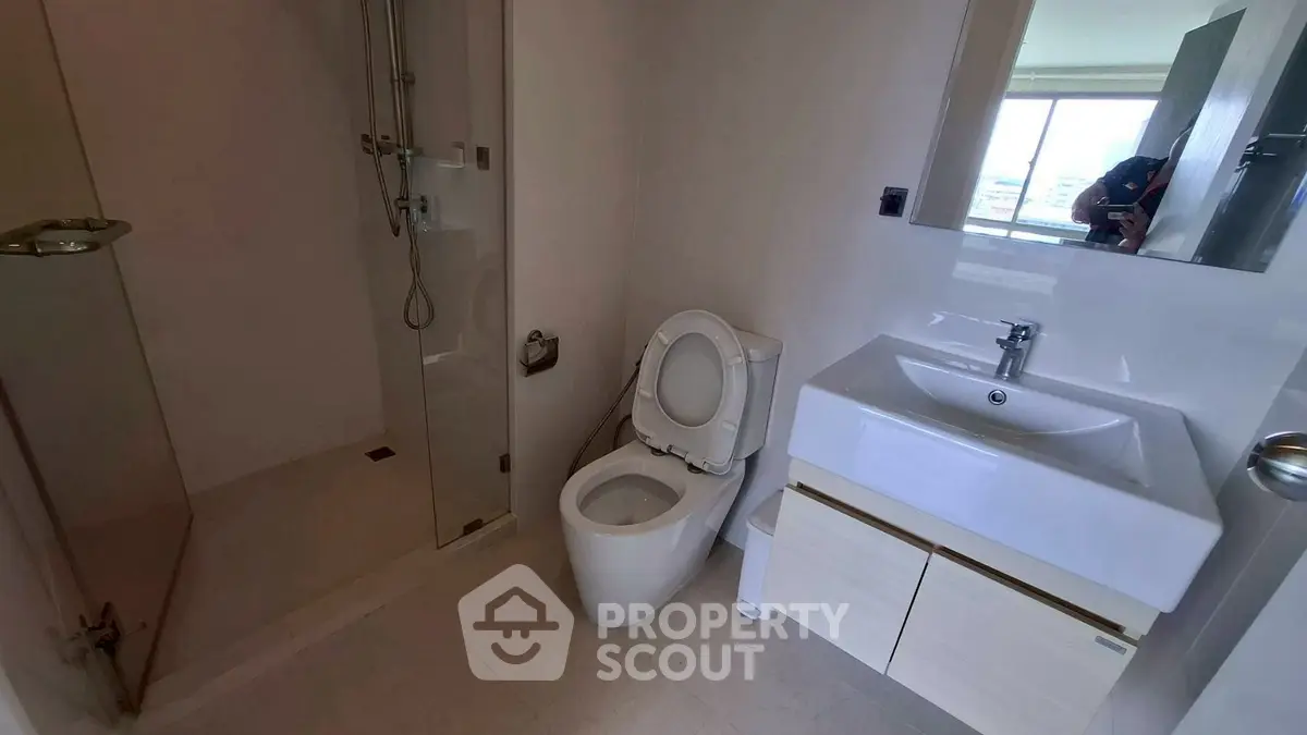 Modern bathroom with sleek fixtures and glass shower in a contemporary apartment.