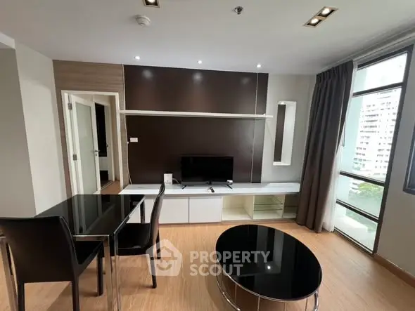 Modern living room with sleek furniture and large windows offering city views.