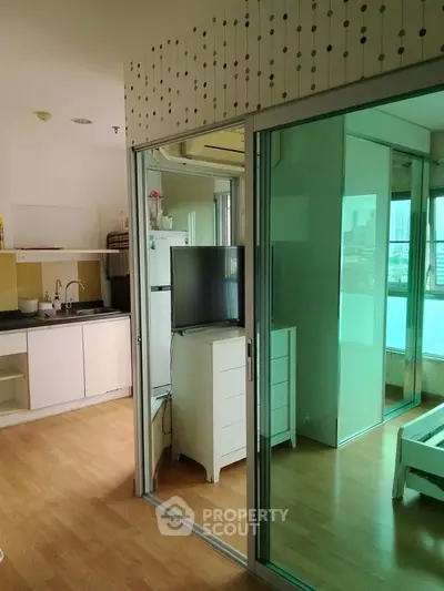 Modern apartment interior with open kitchen and sliding glass doors leading to a bright bedroom.