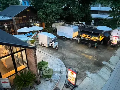 Charming outdoor commercial space with food trucks and cozy seating area, perfect for a vibrant dining experience.