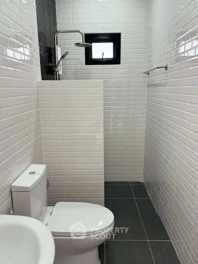 Modern minimalist bathroom with sleek white tiles and compact design.