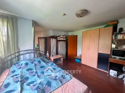 Spacious bedroom with large windows allowing ample natural light, featuring a king-sized bed, wooden flooring, and ample storage with multiple wardrobes.