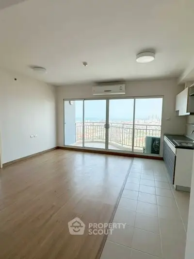 Spacious living room with large windows offering stunning city view and modern kitchen area.