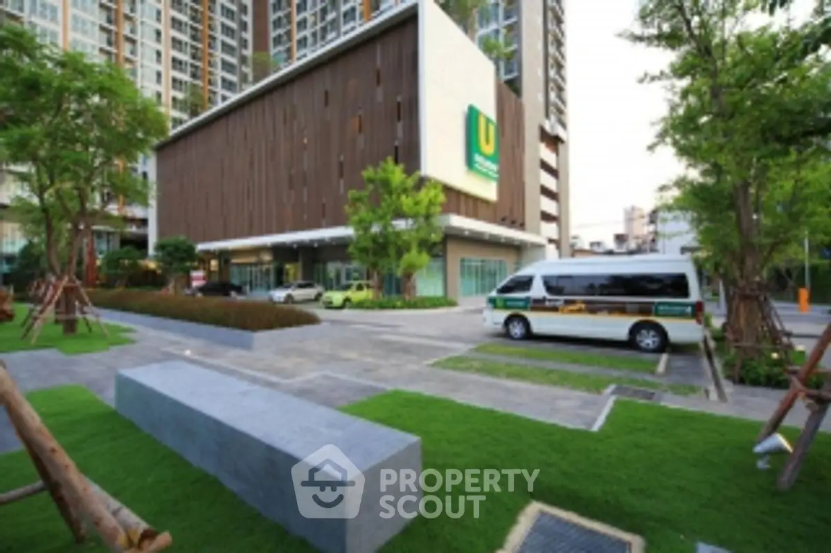 Modern apartment building exterior with lush landscaping and parking area.