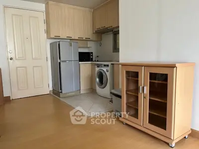 Compact kitchen with fridge, washing machine, and microwave in modern apartment.