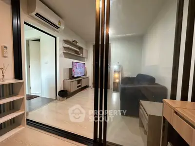 Modern living room with sleek design and glass partition, featuring a cozy sofa and wall-mounted TV.