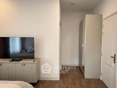 Modern bedroom with sleek TV stand and wardrobe, featuring minimalist design and wooden flooring.