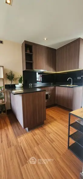 Modern kitchen with sleek wooden cabinetry and black countertops in a stylish apartment.