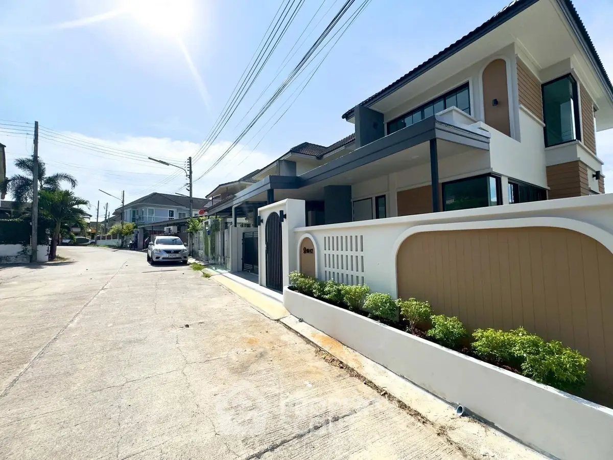 Modern two-story house with sleek design in a sunny suburban neighborhood.
